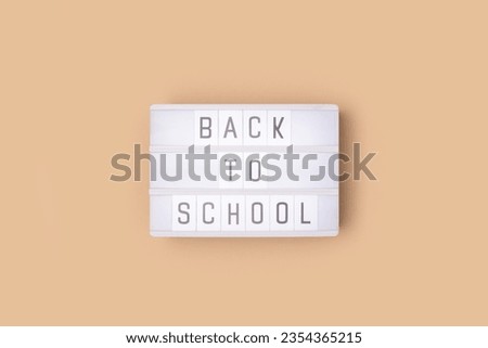 Back to school. White lightbox with letters on a beige background. 