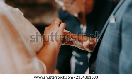 Newlyweds exchange rings, groom puts the ring on bride's hand.