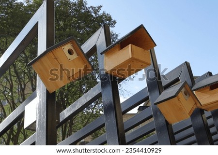 Row with small wooden birdhouses.  Royalty-Free Stock Photo #2354410929