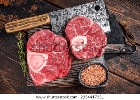 Raw Osso buco Veal shank ready for cooking, raw cross cut calf shank on a butcher board. Wooden background. Top view. Royalty-Free Stock Photo #2354417331