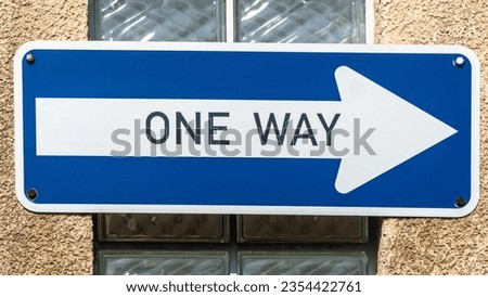 One Way Sign attached on a house facade with glass blocks.