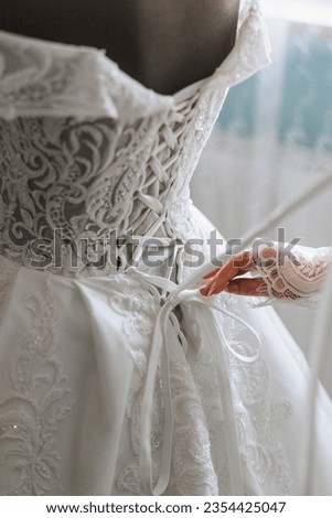 Close-up photo of a beautiful bride untying her wedding dress on a mannequin and getting ready to put it on