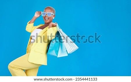 Fashion, sale and black woman with shopping, bag and glasses in studio excited and smile on blue background. Retail, store and African female customer happy with boutique, discount and mall deal