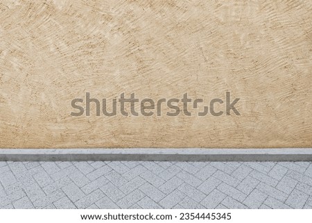Textured background of a light beige or cream painted concrete wall on a street with a view of part of the road Royalty-Free Stock Photo #2354445345