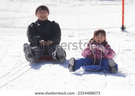 Parent and child playing on a sled
