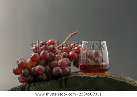 Bunch of purple grapes and glass of whiskey, black background