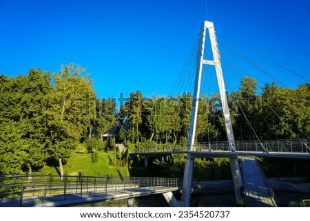 Modern footbridge with steel cables across the Anhor canal in Navruz park in summertime day, Uzbekistan, Tashkent.