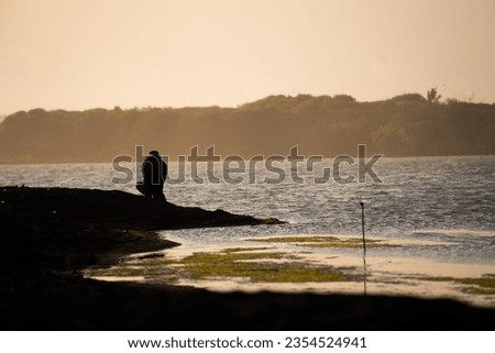 silhouette of an adventurer walking by the seashore and taking pictures, sunset view. motivational concept.