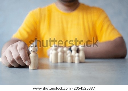 Choosing the right person, hand picking up the best of wooden figures and places in front. Organizational leadership selection concept. Outstanding management ability, individual status Royalty-Free Stock Photo #2354525397