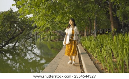Portrait of happy Asian Vietnamese woman travel at Turtle tower in river of Hoan Kiem Lake in public park garden in Downtown Hanoi. Urban city, Vietnam. People lifestyle.