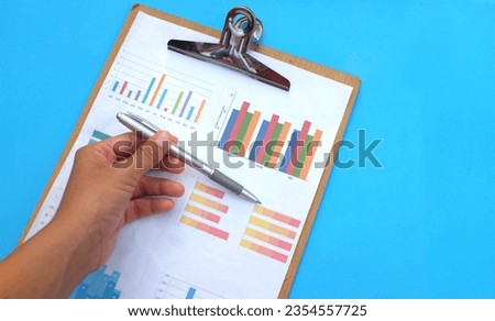 Hand holding a pencil pointing to the graph document on the doctor's desk with stethoscope