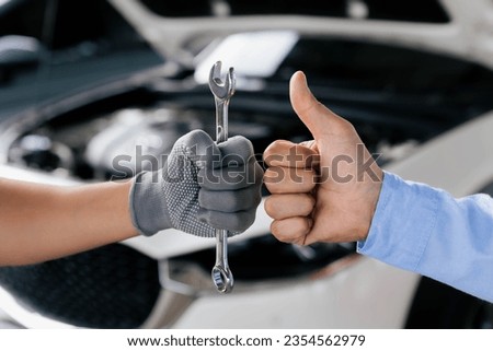Mechanics is holding a spanner while the other is showing thumb up, Technic occupation. Automobile Repair Service Concept. Royalty-Free Stock Photo #2354562979