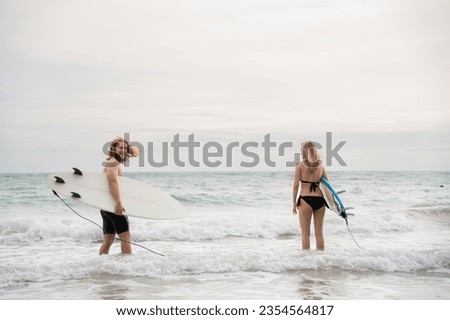 Young man and woman holding surfboards ready to walk into the sea to surf.