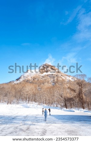 People taking pictures of mountains of the Showa Shinzan Volcano in the Shikotsu-Toya National Park, Hokkaido, Japan.