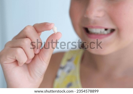 The girl is holding her milk tooth in her hands. Child happy after tooth extraction. Royalty-Free Stock Photo #2354578899