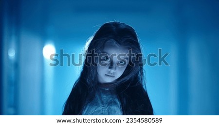 Girl in little white sundress creepily staring into camera, dressed for halloween. Child's ghost in haunted house - halloween costume party 