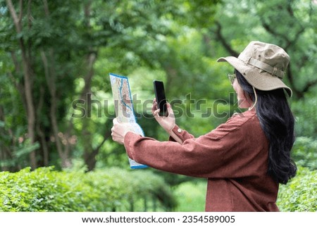 Woman hands with a smartphone and map in the forest background, isolate screen. Happy young woman with a map, smartphone travelling on nature. Travel concept.