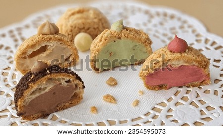 Cream Puffs topped with crumble and Filled with raspberry muslin cream, pistachio muslin, hazelnut praline muslin, diplomat  cream and chocolate cream. Royalty-Free Stock Photo #2354595073
