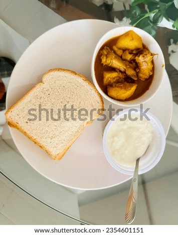 breakfast with bread, chicken curry and   fresh yoghurt mixed coconut. an Indian breakfast .