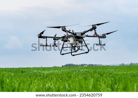 Drone flying over a green grass field with cloudy sky in the background Royalty-Free Stock Photo #2354620759