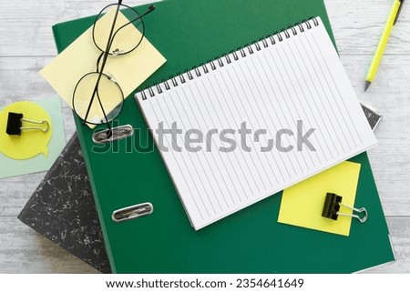 blank notepad, green folder and yellow glasses sticker. Top view with copy space, flat lay.