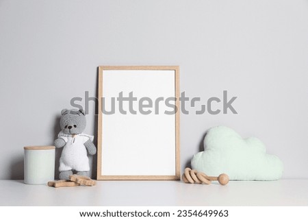 Empty square frame and different toys on white table