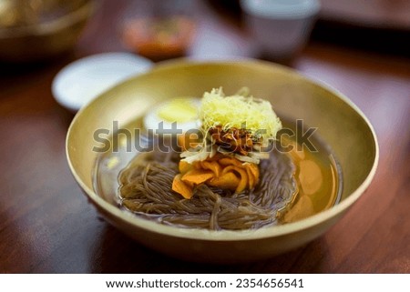 Delicious bowl of fresh Mul Naengmyeon, also called Pyongyang noodles: dish of North Korean origin which consists of long and thin handmade noodles,  served with a spicy dressing Royalty-Free Stock Photo #2354656541