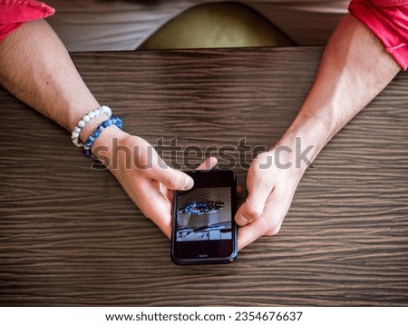 Photo of a person using a cellphone at a table