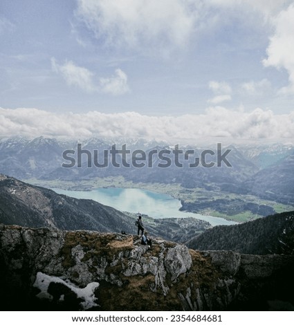 A couple of hikers admire the view of the wolfgangsee in austrian alps.