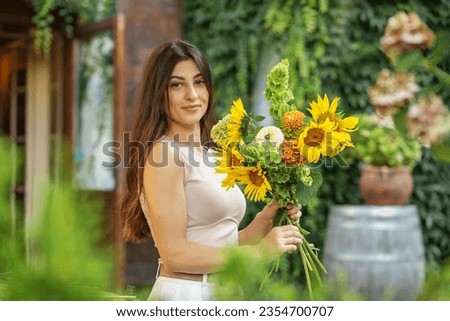 Startup successful small business entrepreneur owner woman standing with flowers and makes bouquet.