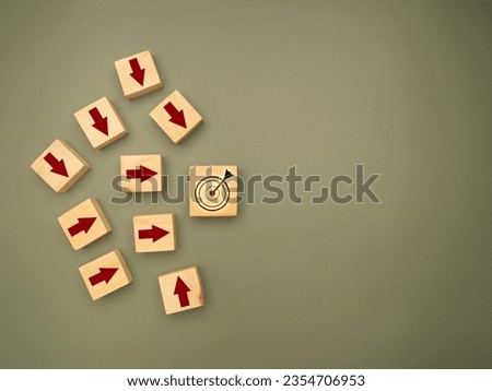 Focus on a goal and achieve a successful business concept. Wooden cubes with red arrows pointing to the dartboard icon are on a green background. Top view. Business and planning concept