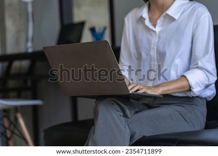 Side view of business woman's hands using laptop computer resting, young woman writing in blank notebook placed on office table with laptop keyboard close up pictures