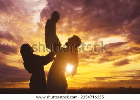 Silhouette of Happy arabian family playing together over sunset