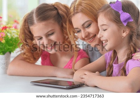 Mother and girls sitting at table and using laptop. High quality photo