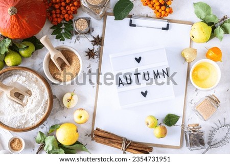 Autumn flat lay with lightbox with the phrase Autumn. Top view. Food ingredients for making autumn pumpkin pie on a white stone background. Homemade baking.