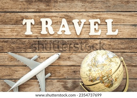 Word Travel, airplane and globe on wooden background.