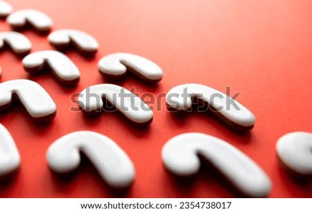 A lot of gingerbread candy cane shaped cookies on a red background.