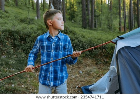 cute caucasian boy putting up a tent. Family camping conceptsunset shadows from trees. Family camping concept. High quality photo