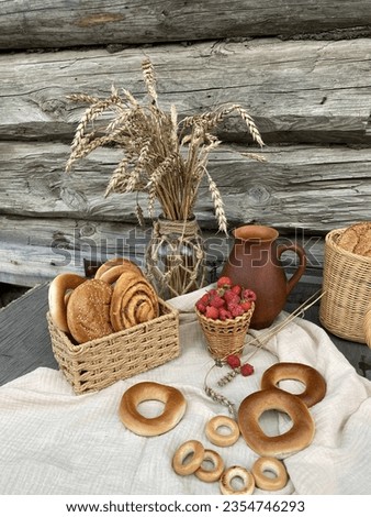 bakery products in a wicker basket with berries in a basket with rye wheat in a vase on a linen tablecloth close-up side view against an old wooden wall rustic style