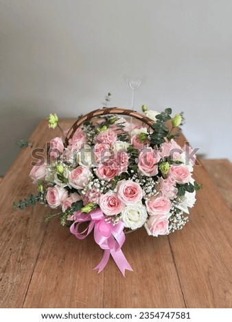 Beautiful colourful blossoming basket of fresh blossoming flowers, close up view. White and pink rose boquete on wooden table