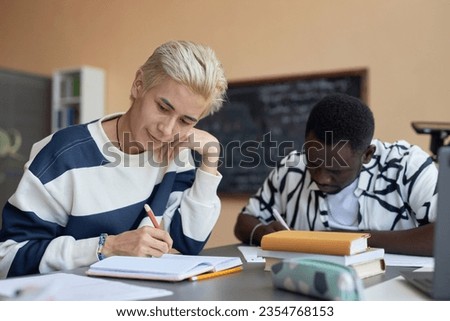 Young Asian man with dyed blond hair looking through test questions