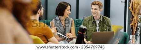 happy young entrepreneurs with laptop and documents near blurred colleagues in modern office, banner