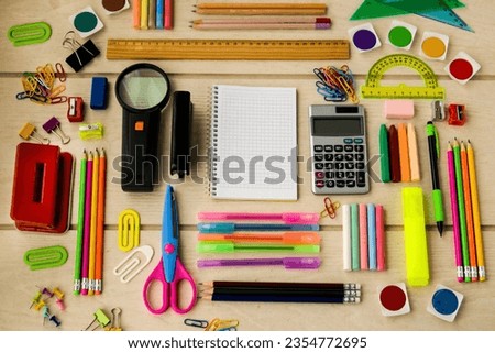 Colorful school supplies designed on wooden table, with blank checkered notebook,Conceptual image of education