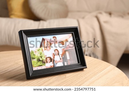 Frame with family photo on wooden table indoors. Space for text