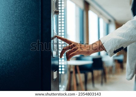 Close up view of woman's finger pushing number button on keyboard of snack vending machine. Self-used technology and consumption concept Royalty-Free Stock Photo #2354803143