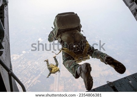 The back of Rangers parachuted from military airplanes, Thai Soldiers parachuted from the plane, isolated airborne soldier, practice parachuting, Paratroopers jumping from an airplane. Royalty-Free Stock Photo #2354806381