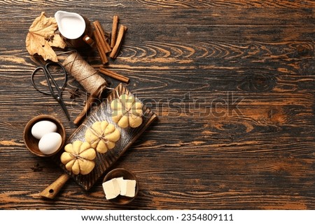 Pumpkin shaped buns and ingredients on wooden background