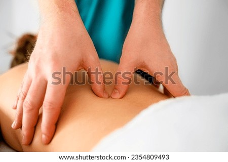 Skilled massage therapist's hands doing massage of trigger points in the back in the massage parlor Royalty-Free Stock Photo #2354809493
