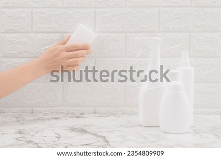 White sponge in hand cleaning wall tiles with cleaning product on marble table. Cleaning concept and household. Melamine. Royalty-Free Stock Photo #2354809909
