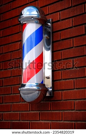Barber shop sign spinning pole red white and blue on brick wall